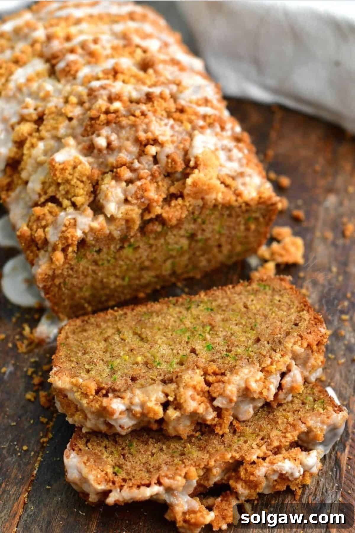Zucchini Loaf Perfection 2 Slices of moist zucchini bread with cinnamon streusel and a whole loaf on a rustic wooden board, ready to be enjoyed.