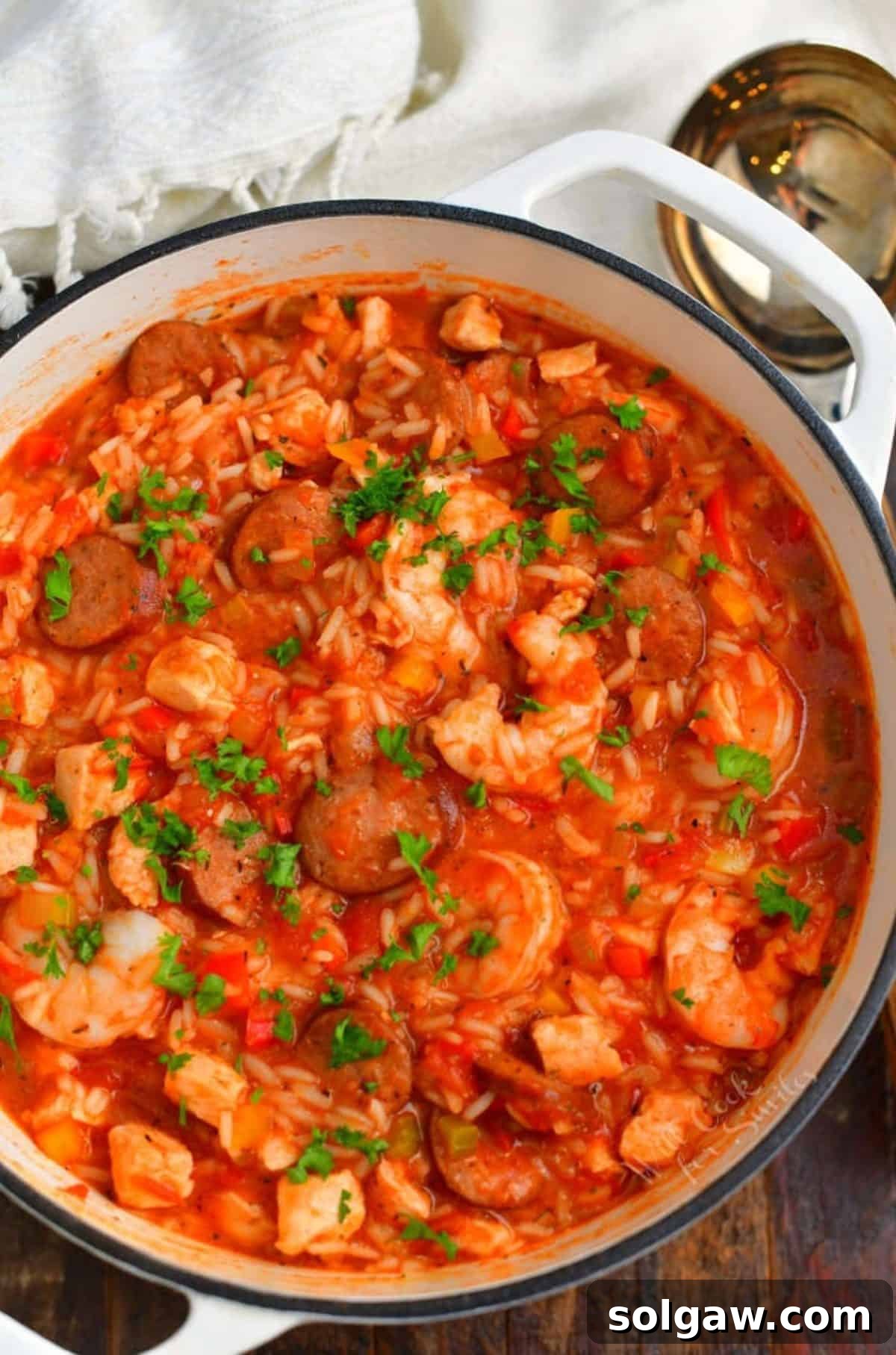 Classic spicy New Orleans Jambalaya in a white Dutch oven pot with a ladle resting beside it, ready to be served.