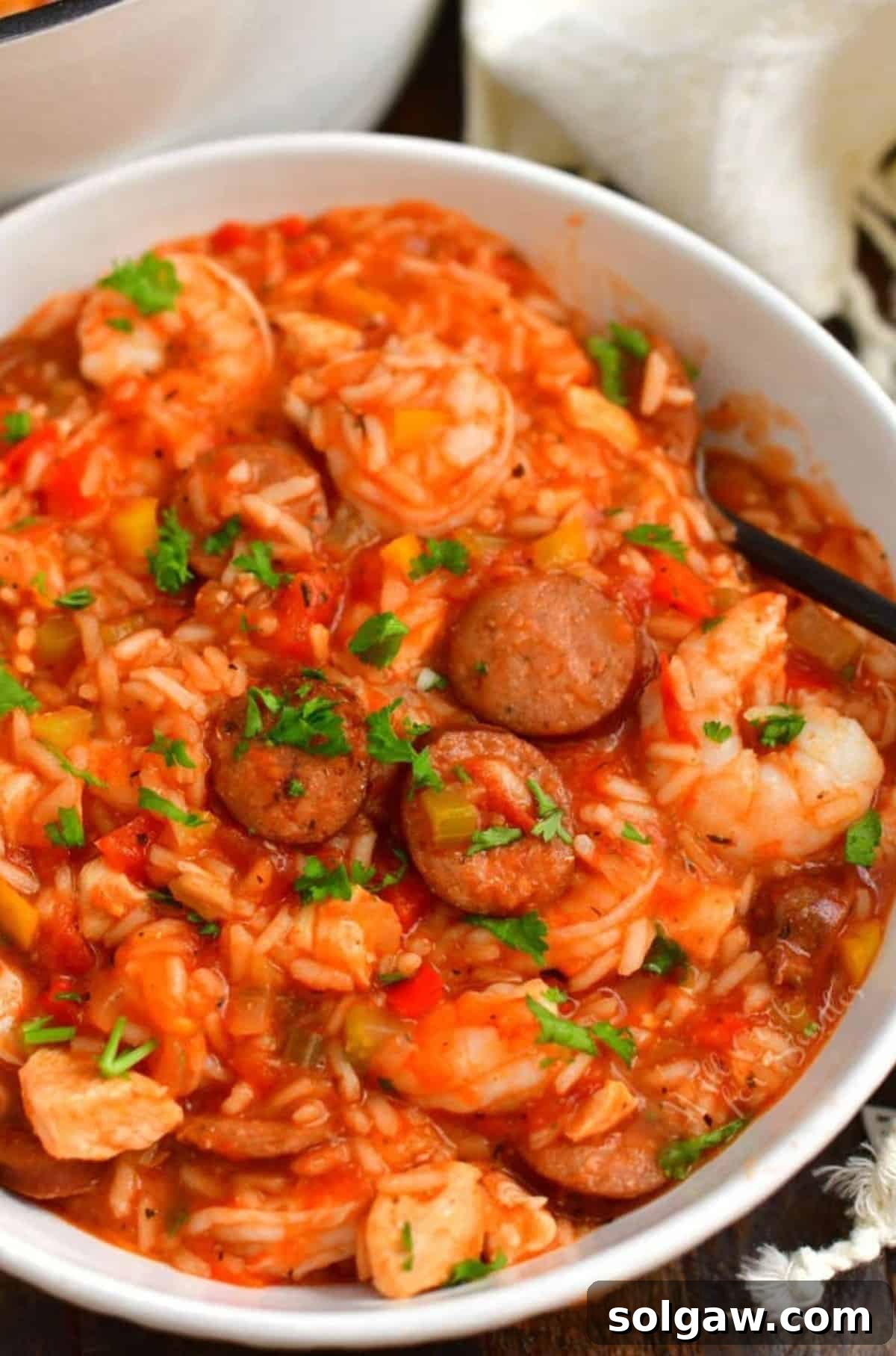 A perfectly portioned bowl of Jambalaya, garnished with fresh parsley and a spoon, inviting you to savor its rich flavors.