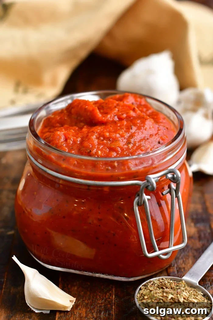 homemade pizza sauce with tomato paste in small glass jar on wooden counter top