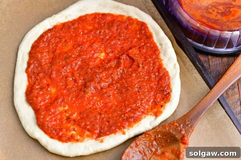 layer of homemade pizza sauce on unbaked pizza crust