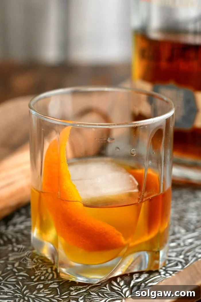 side view: whiskey old fashioned in low ball cocktail glass with orange peel