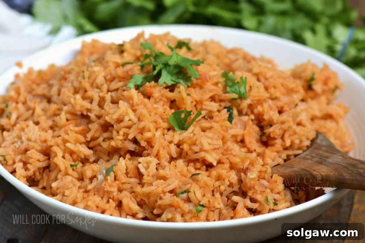 A bowl of red-orange Spanish rice with a wooden spoon, ready to be enjoyed.