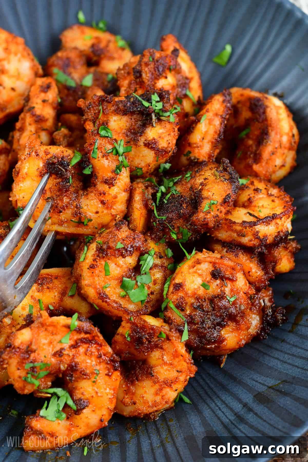 Smoky Cajun Shrimp 2 several cooked blackened shrimp in a bowl with a fork.