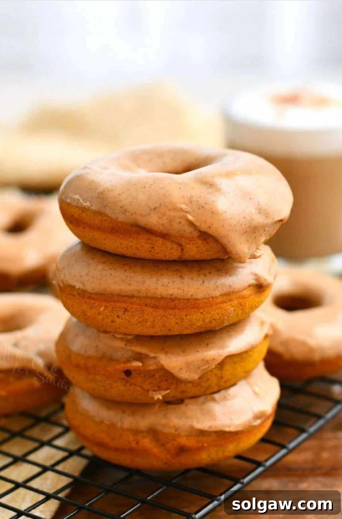 Homemade Pumpkin Spice Latte Donuts 2 Stack of four baked pumpkin donuts with pumpkin spice latte glaze on a wire rack, evoking cozy autumn mornings.