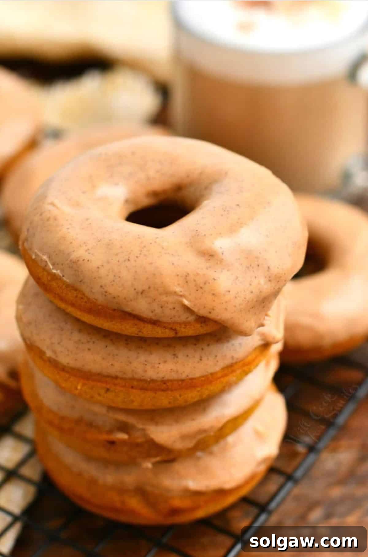 Stack of four pumpkin spice baked donuts with glaze on top.