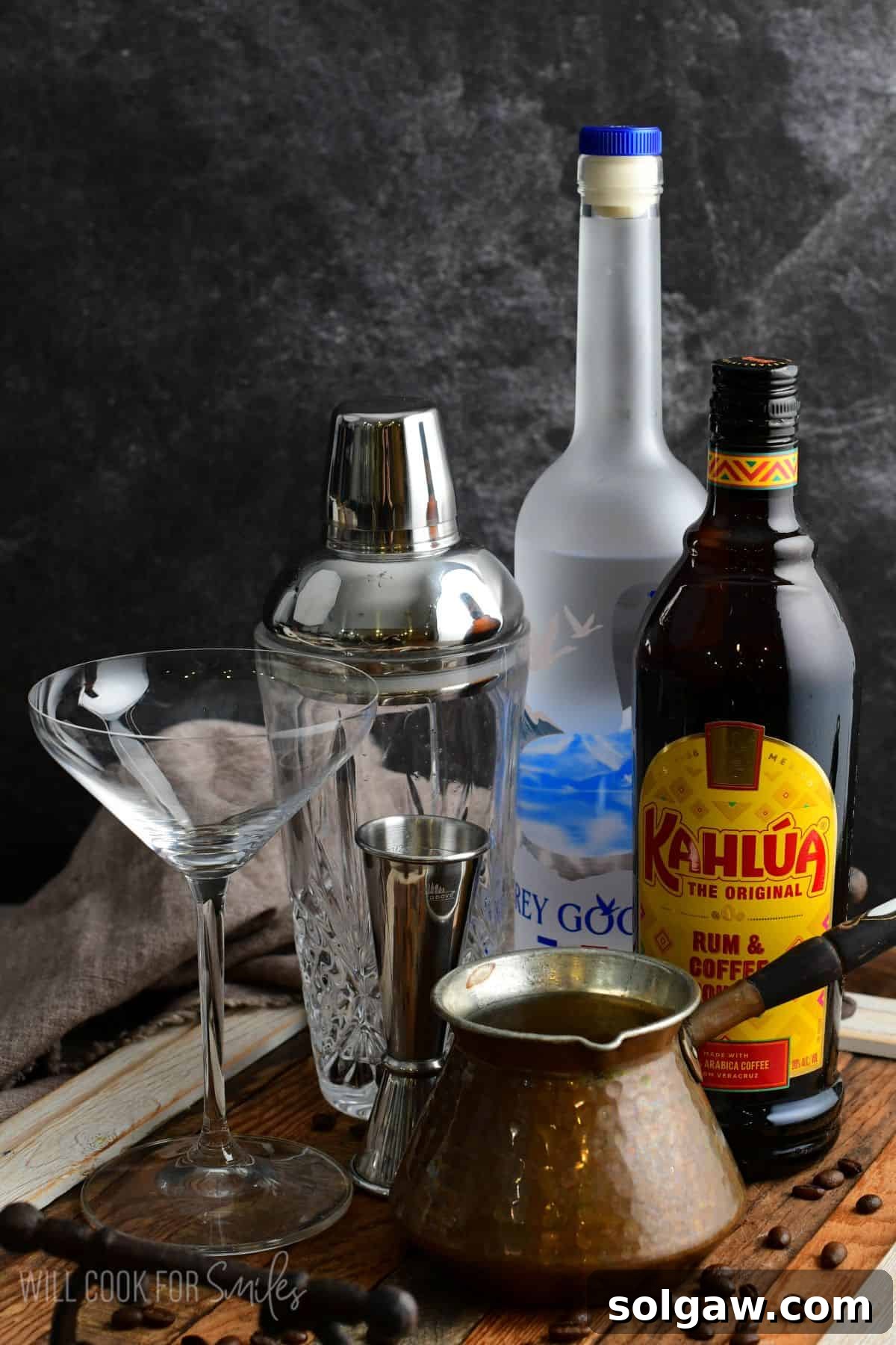 Key ingredients for espresso martini laid out on a rustic wood surface, including vodka, coffee liqueur, and coffee beans.