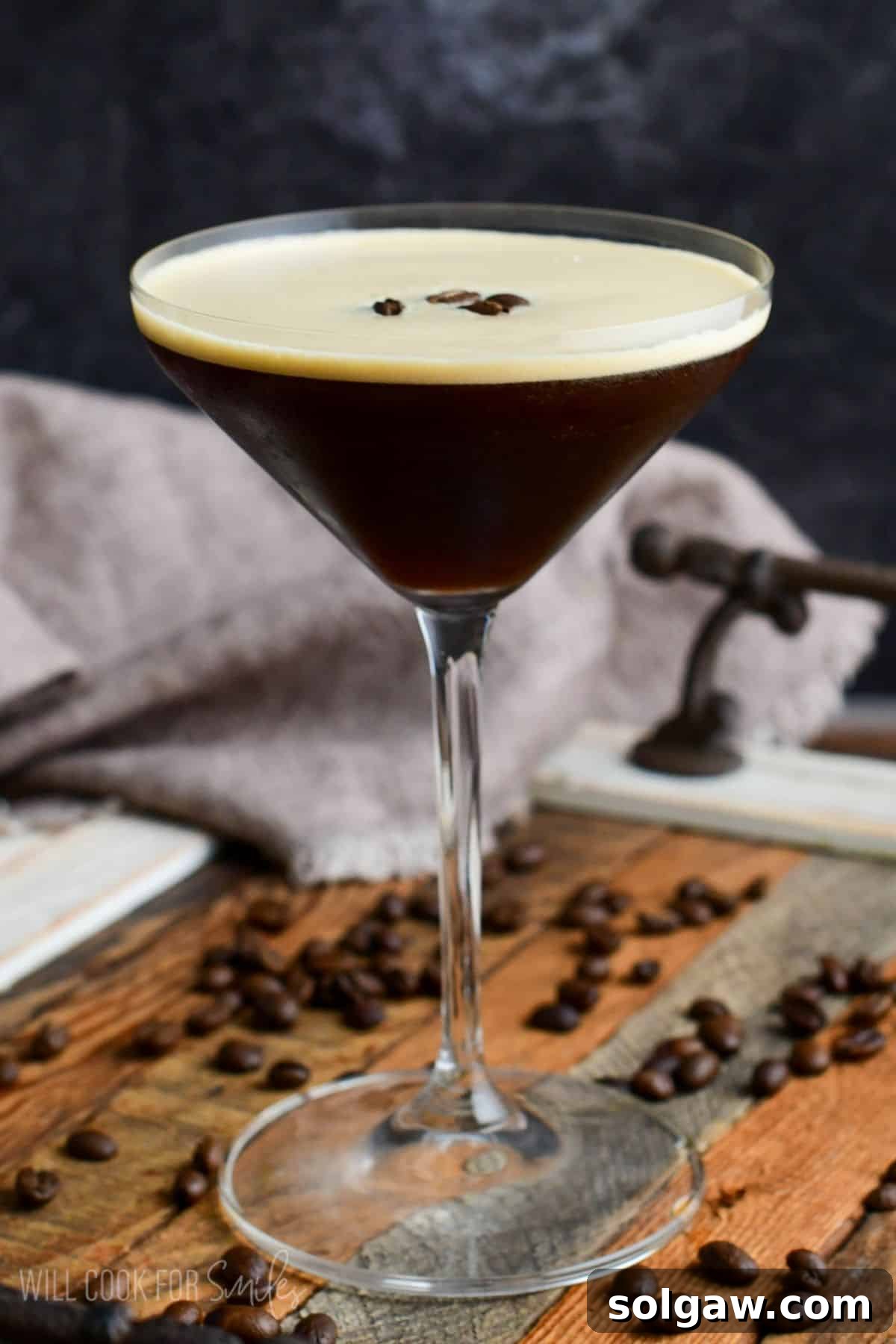 Espresso martini in a glass on a wood surface with espresso beans as garnish.