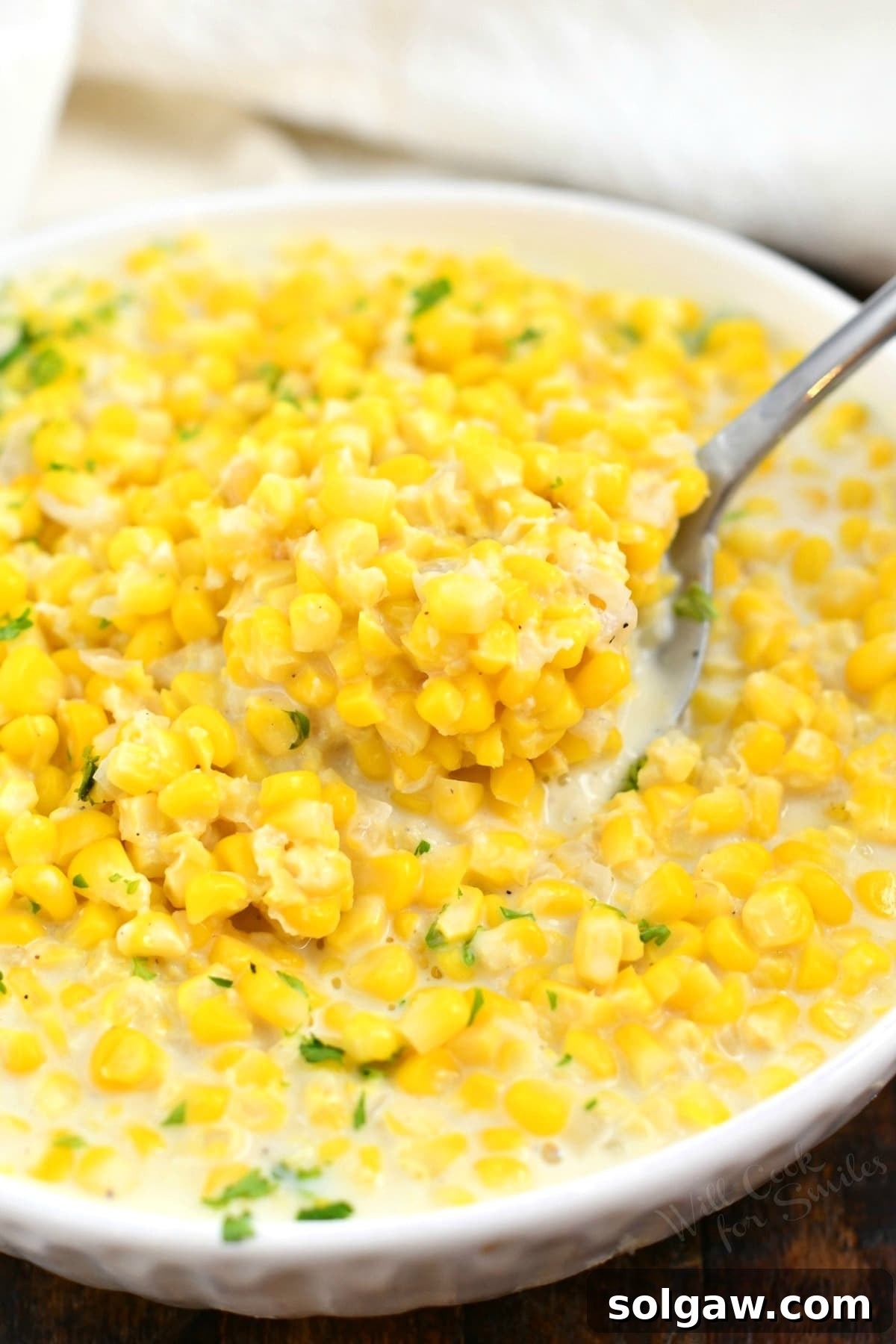 overhead closeup: spoonful of creamed corn in a bowl