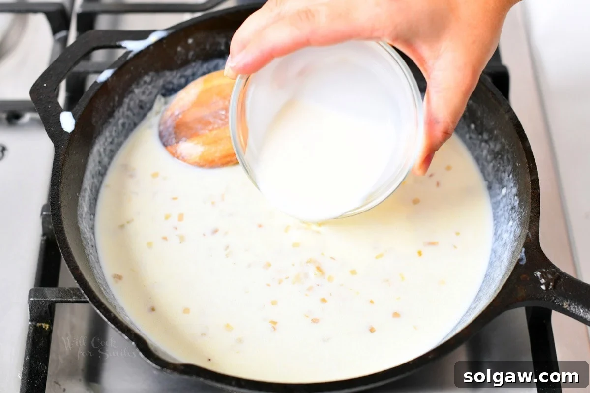 overhead image: pouring heavy cream into a cast iron skillet