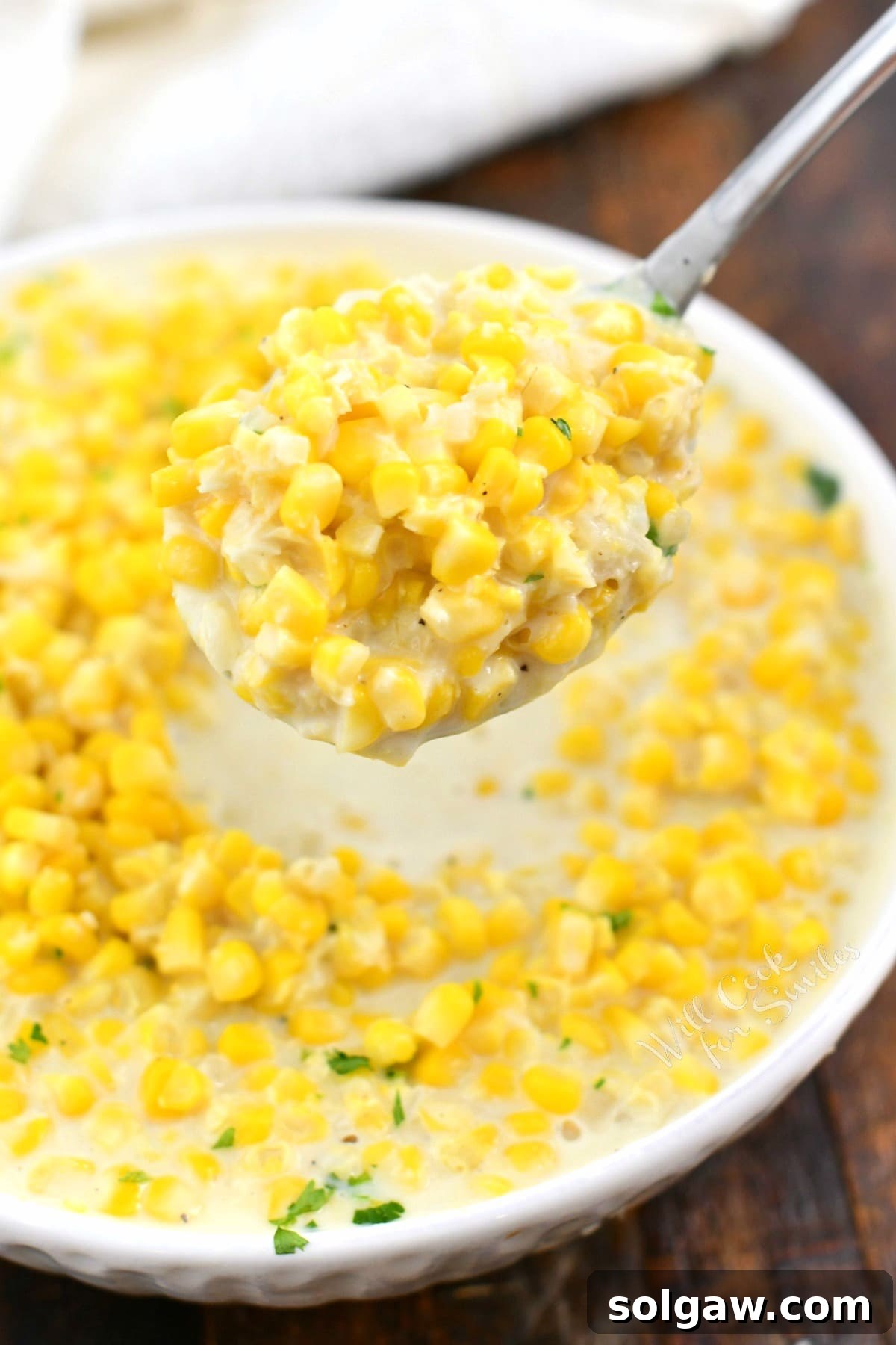 creamy corn side dish in white bowl and on serving spoon above it