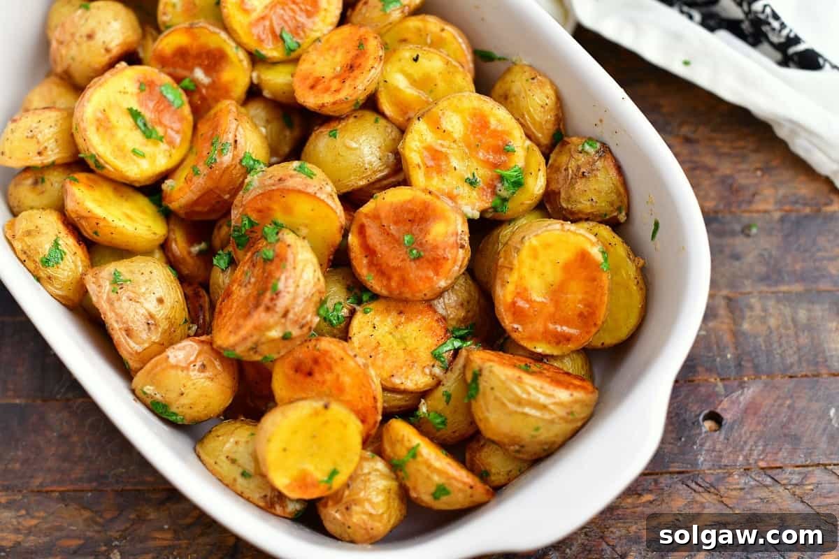 White dish of oven roasted potatoes with parsley and melted butter, beautifully presented.