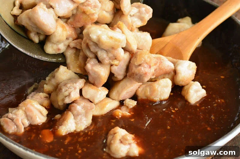 seared chicken pieces being added to the simmering bourbon sauce
