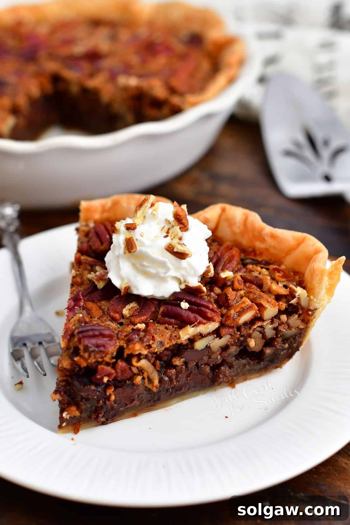 A beautifully plated slice of chocolate pecan pie topped with fresh whipped cream, ready to be enjoyed.