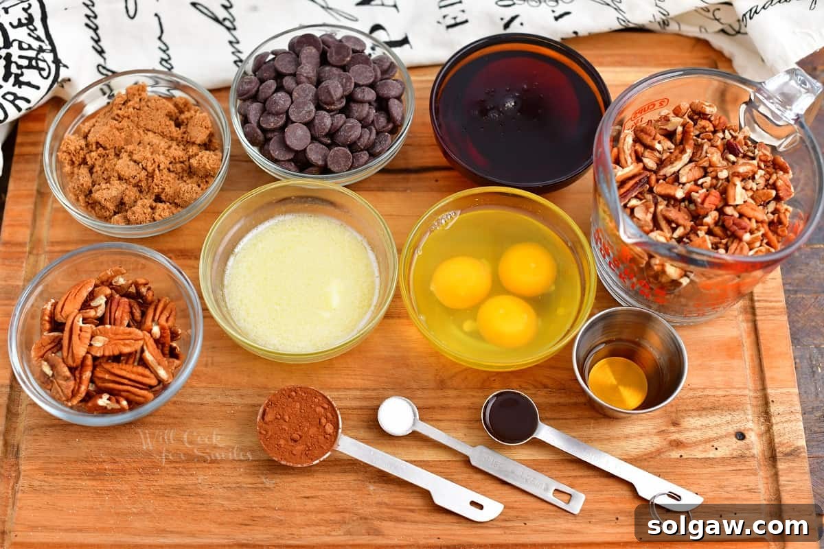 Ingredients for chocolate pecan pie laid out in prep bowls on a wooden cutting board.
