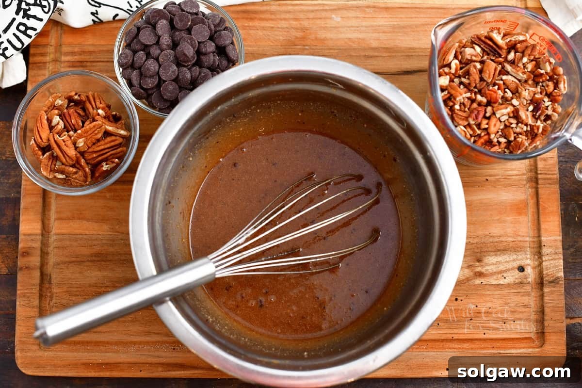 Various ingredients for chocolate pecan pie neatly arranged in small bowls on a wooden cutting board.