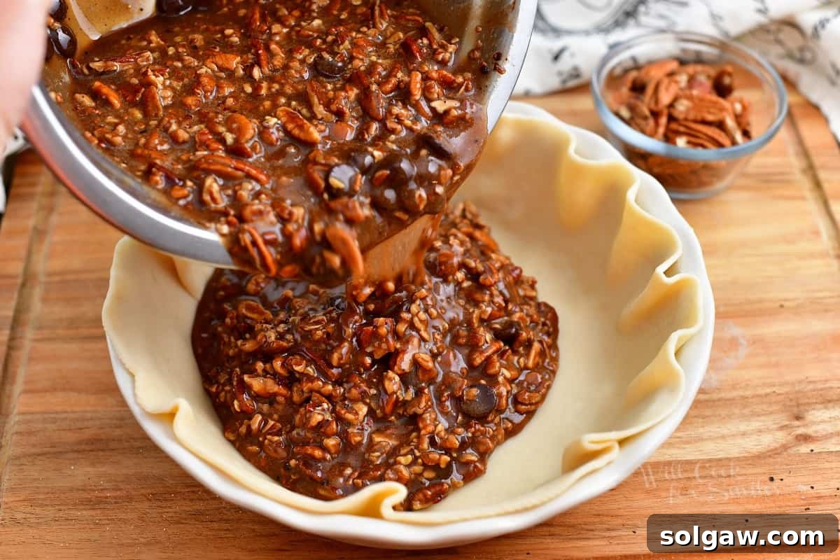 Pouring the rich, chocolate pecan pie filling into a prepared pie crust.