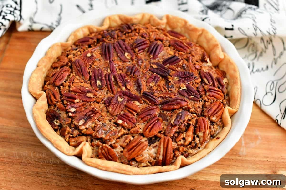 A baked holiday pecan pie, garnished with whole pecans, perfect for Thanksgiving.