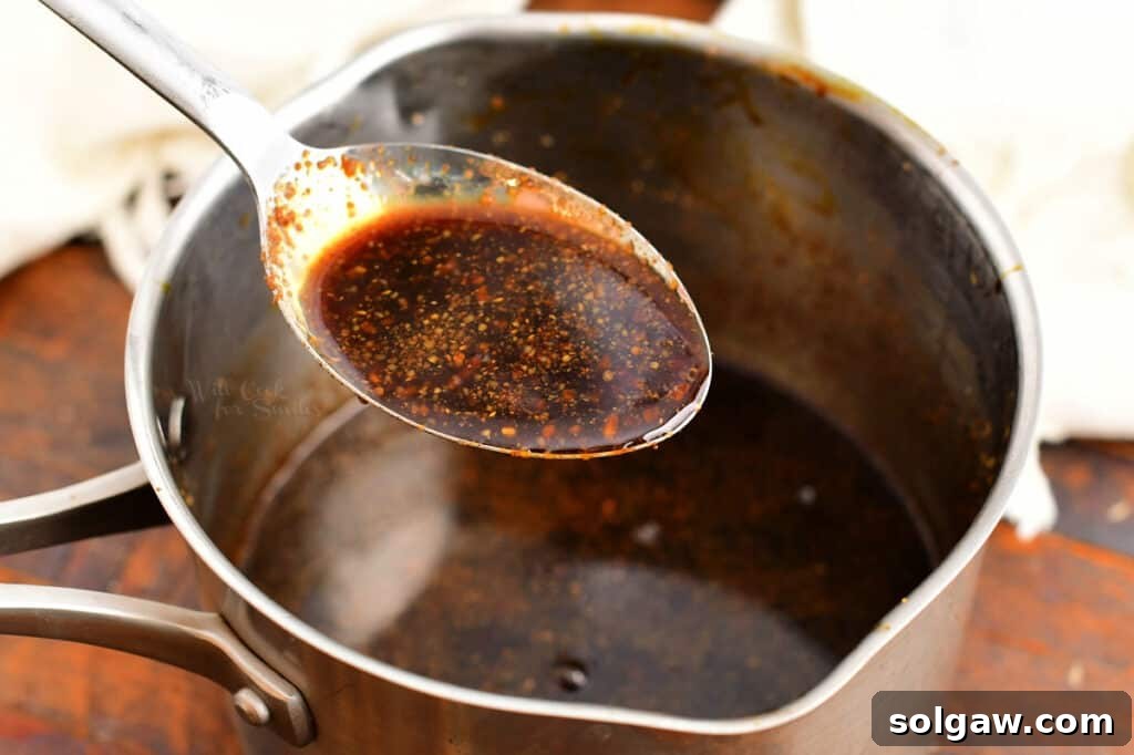 Signature Bourbon Glazed Ham 3 Close-up of a spoon drizzling rich, amber bourbon glaze over a saucepan, showcasing its perfect consistency.