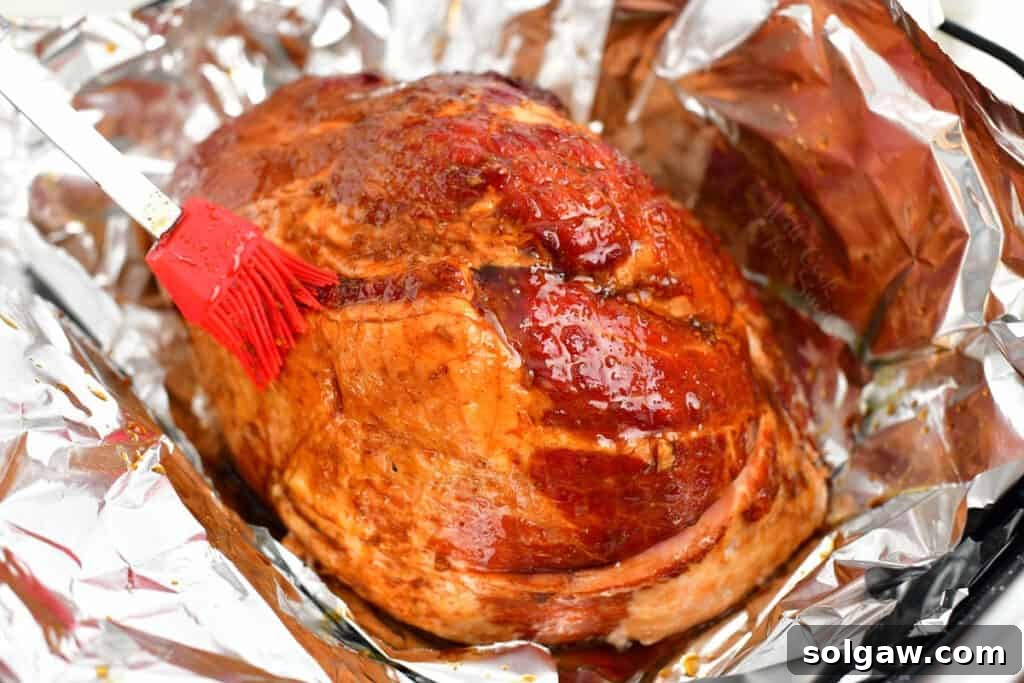 Signature Bourbon Glazed Ham 4 A chef's brush carefully applying a rich bourbon glaze onto the surface of a smoked ham before baking.