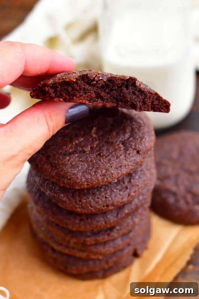 woman's hand holding freshly baked chocolate cookie with bite removed