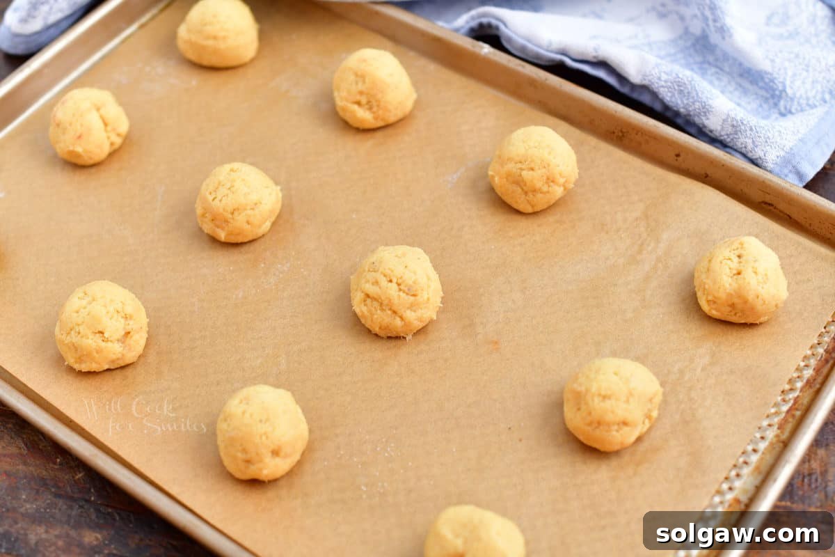 Evenly spaced balls of eggnog cookie dough on a parchment-lined baking sheet.