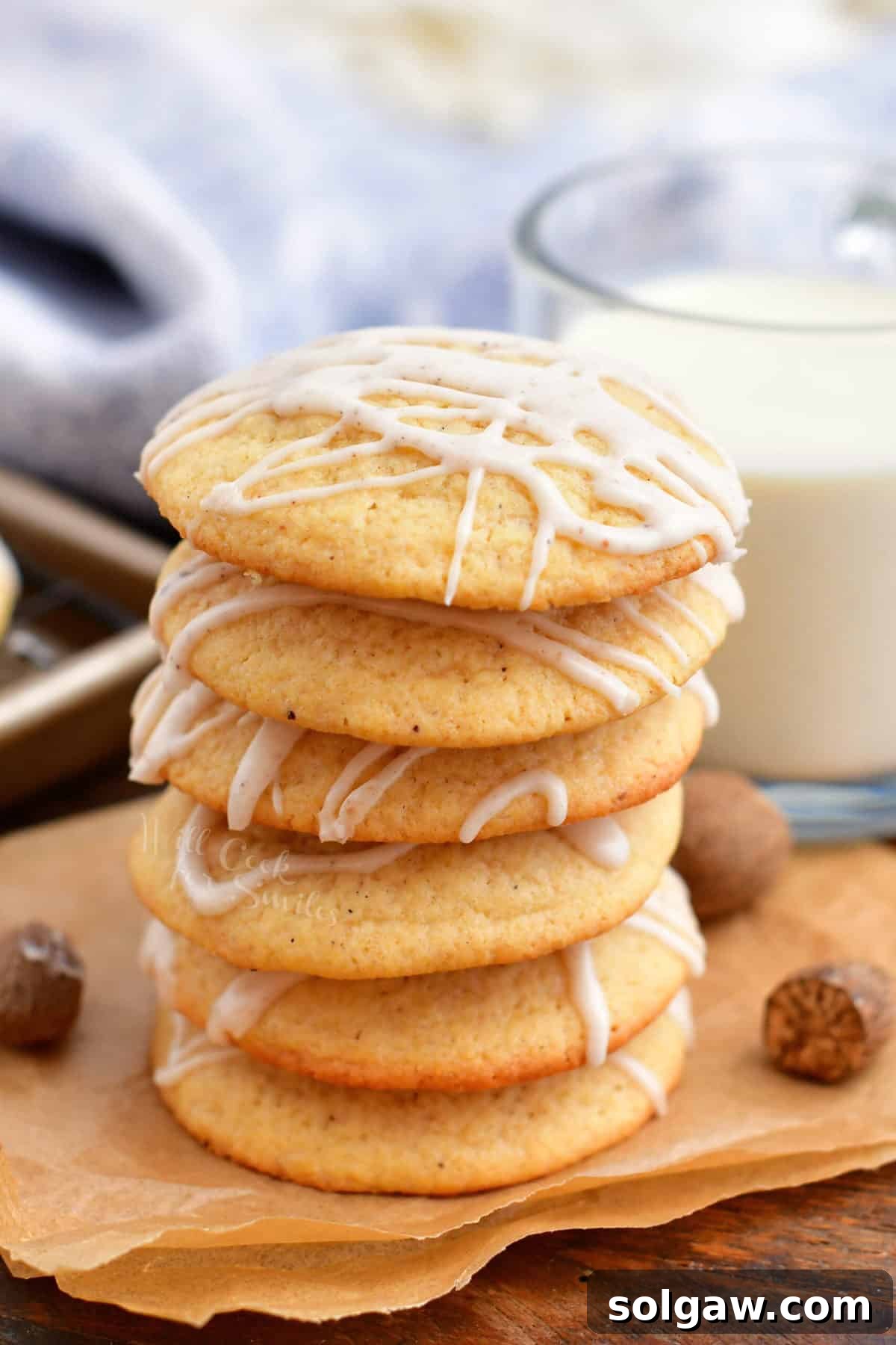 Beautifully iced eggnog cookies stacked next to a refreshing glass of milk, a perfect holiday pairing.