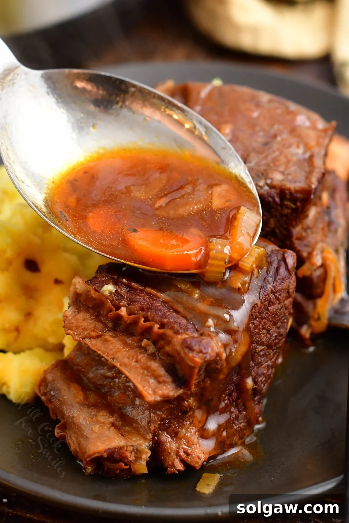 Rich, thickened red wine sauce being poured over delicious Instant Pot short ribs, highlighting their tender texture and the glossy sauce.