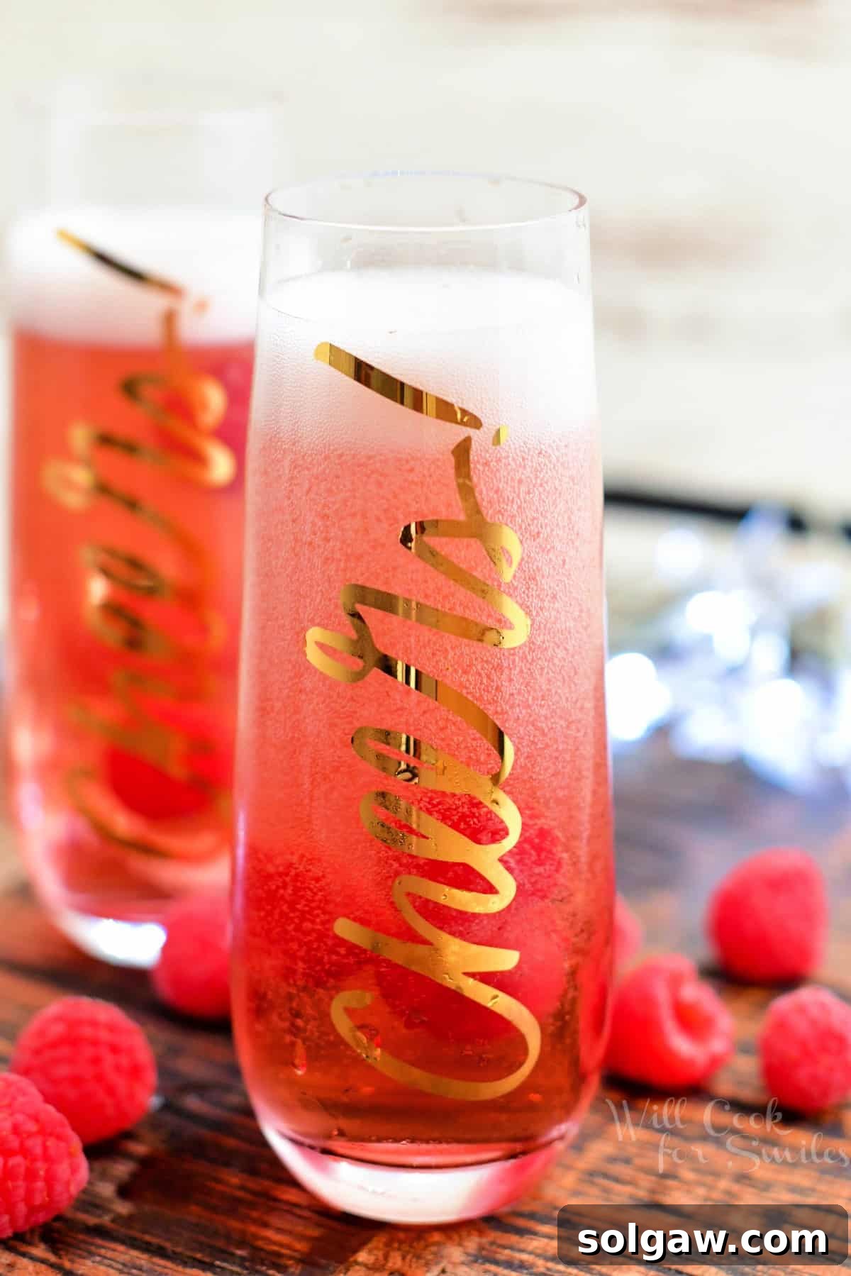 fresh raspberries scattered around two Kir Royale cocktails