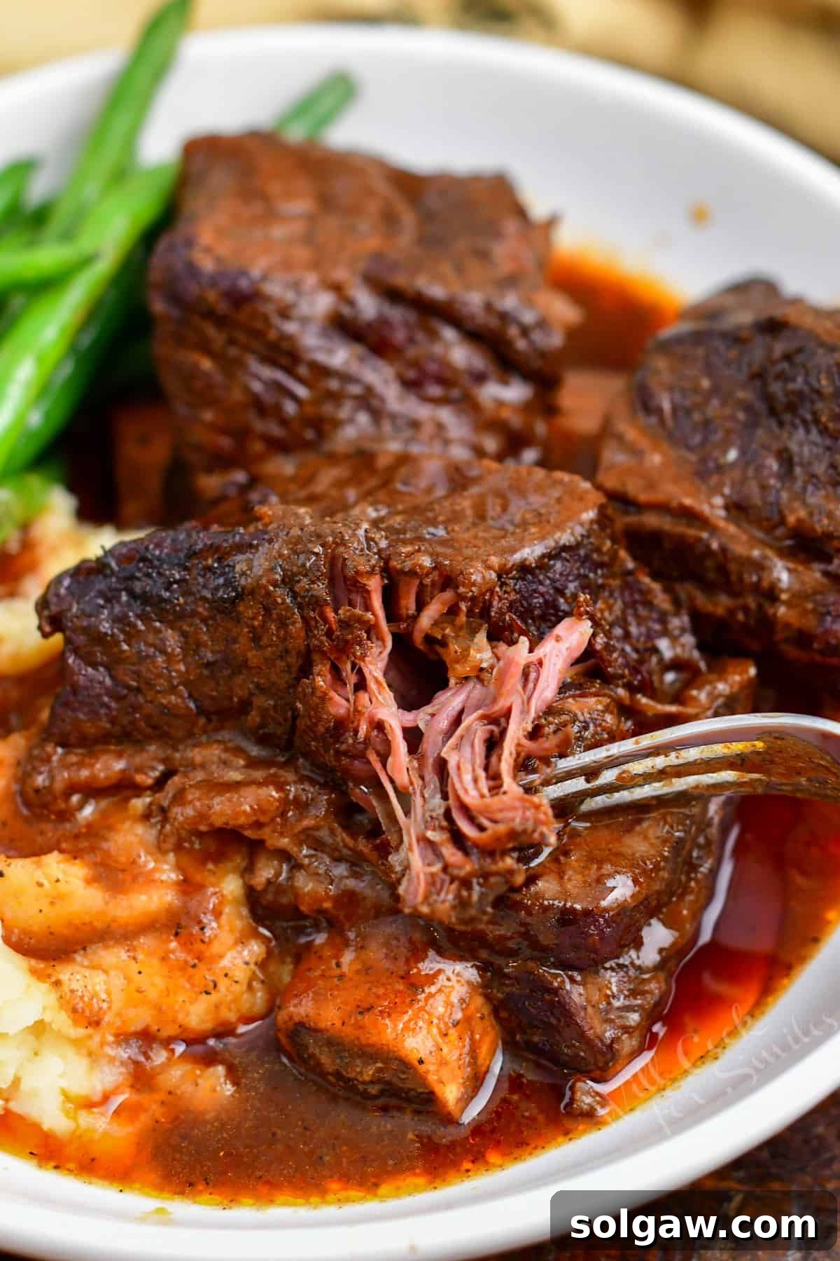 fork pulling tender meat from braised short ribs