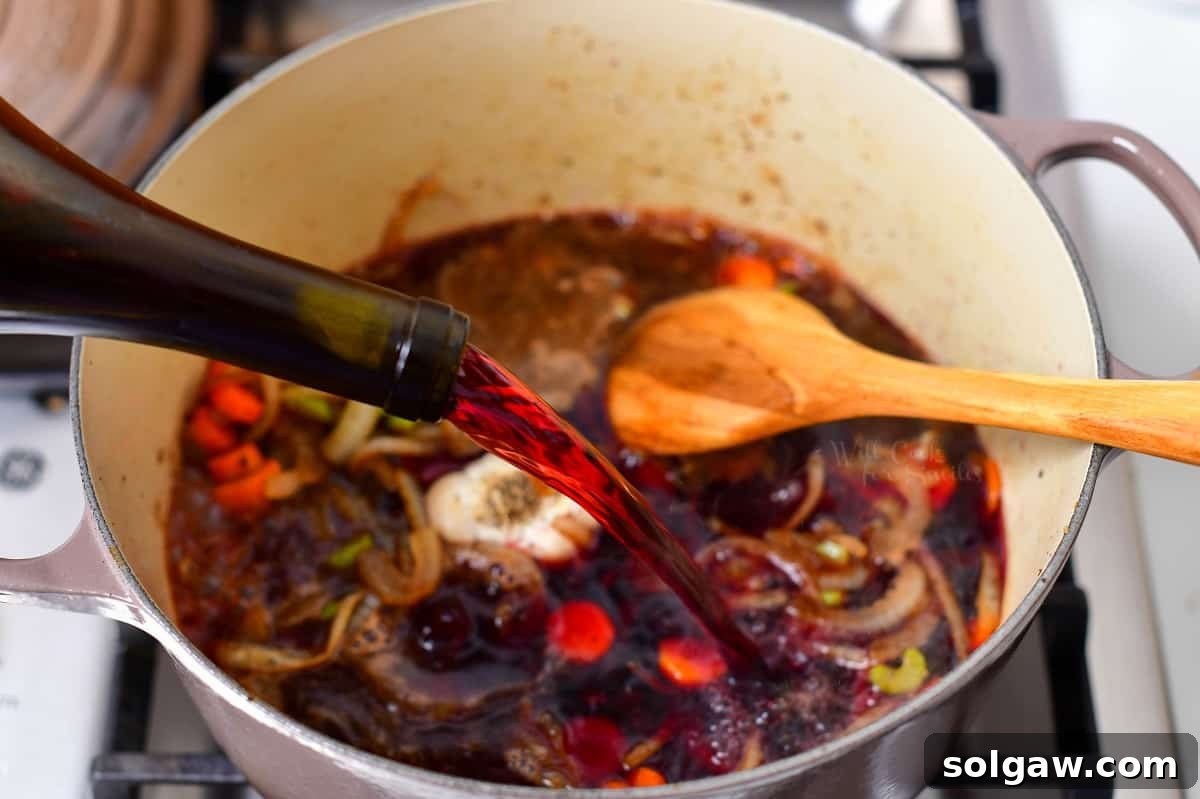 pouring red wine into Dutch oven for a beef short ribs recipe