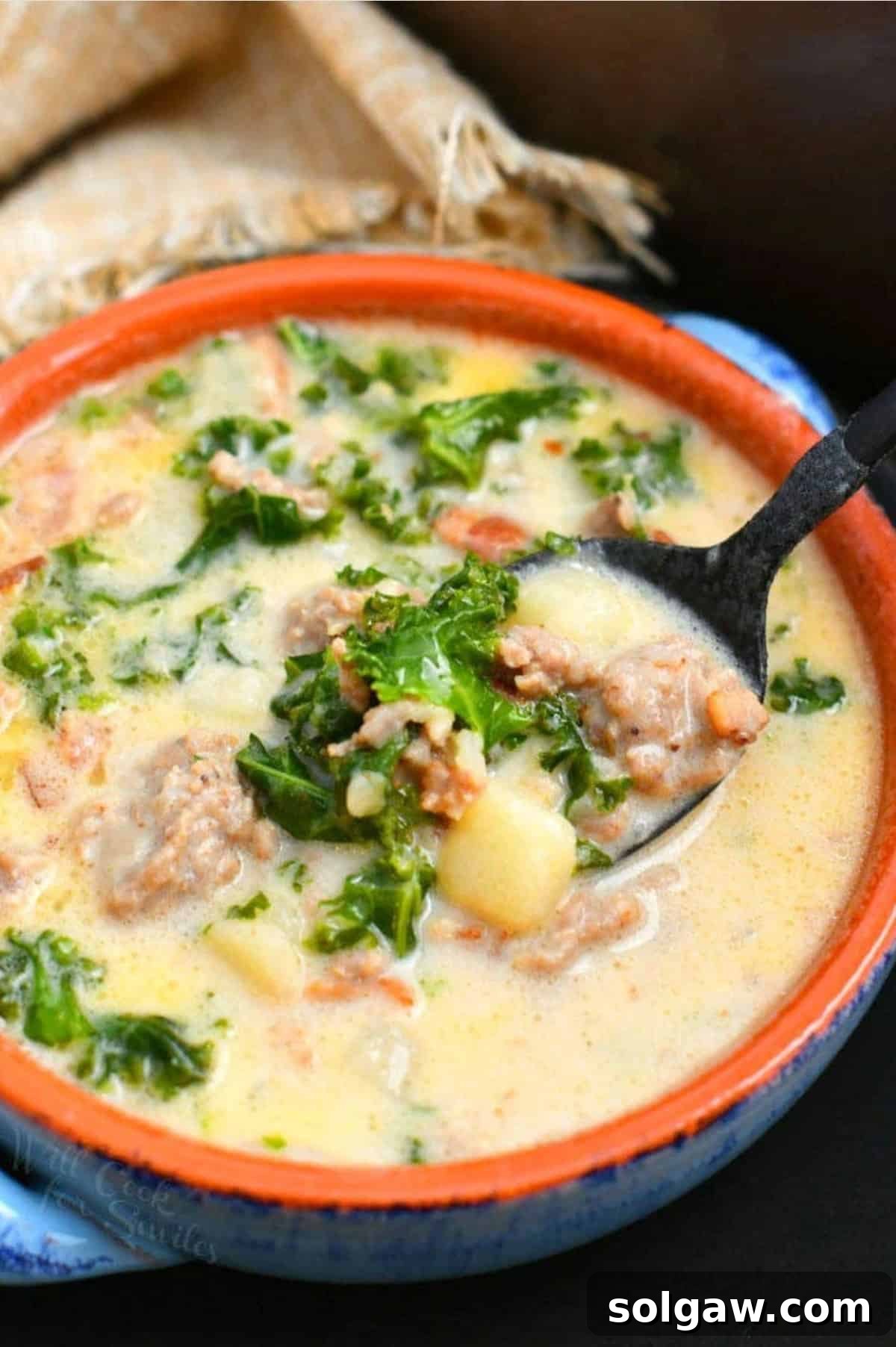 Zuppa Toscana soup in a bowl with a spoon scooping a portion out.