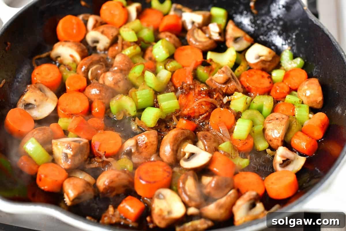 Mushrooms, celery, carrot, and shallot sautéing in a pan of melted butter, building flavor for the fricassee.