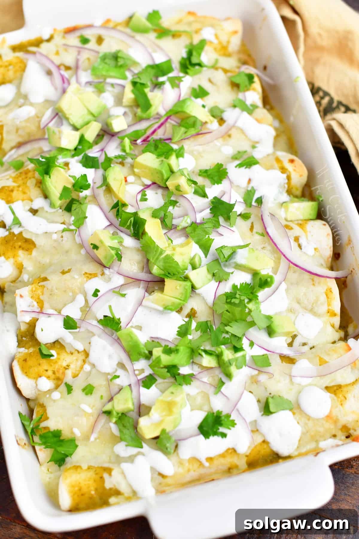 overhead: baked enchiladas verdes in a white casserole dish