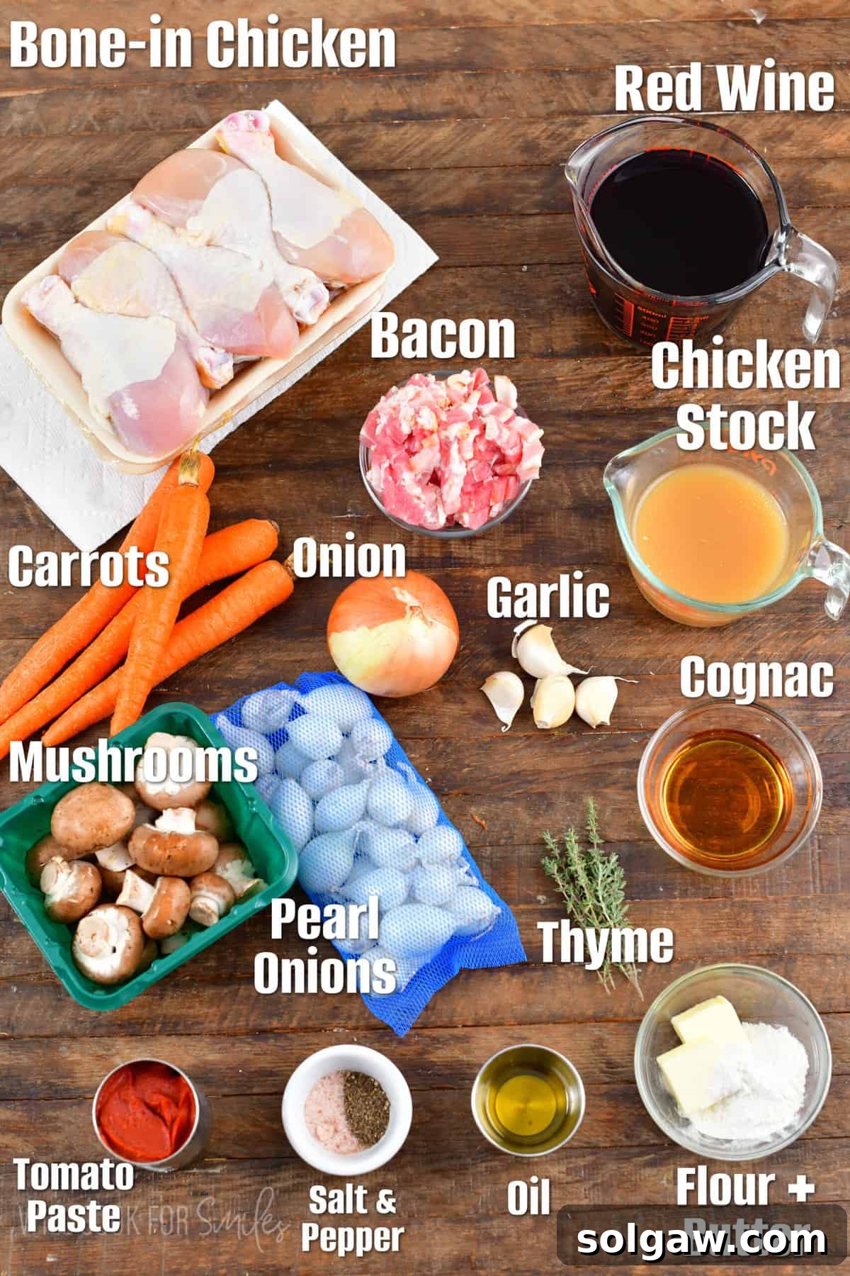 French Wine-Braised Chicken 3 Labeled ingredients for Coq au Vin laid out on a rustic wood surface, including chicken, wine, vegetables, and herbs.