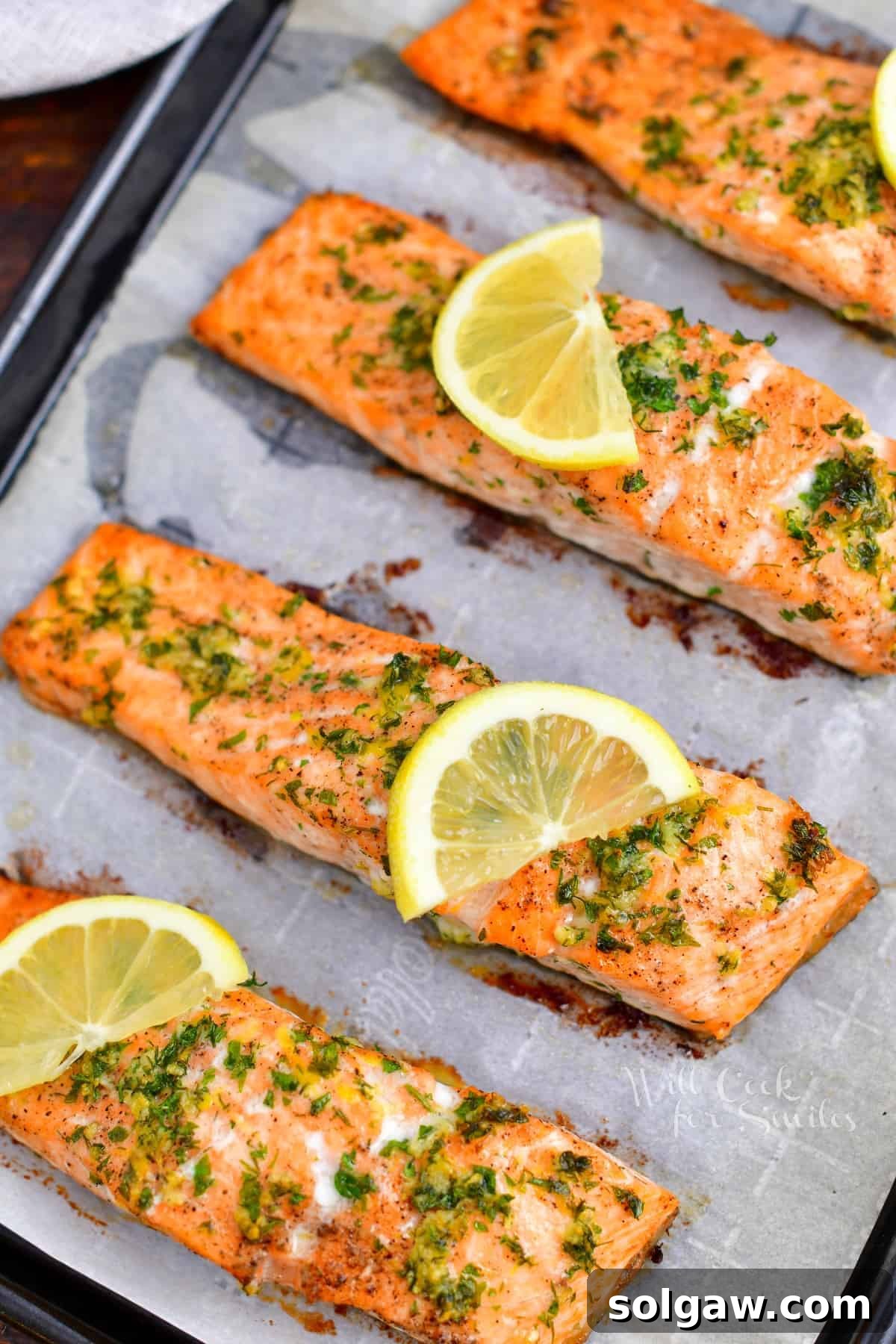 Healthy baked salmon fillets arranged on a parchment-lined baking sheet, topped with lemon slices for an appetizing presentation.