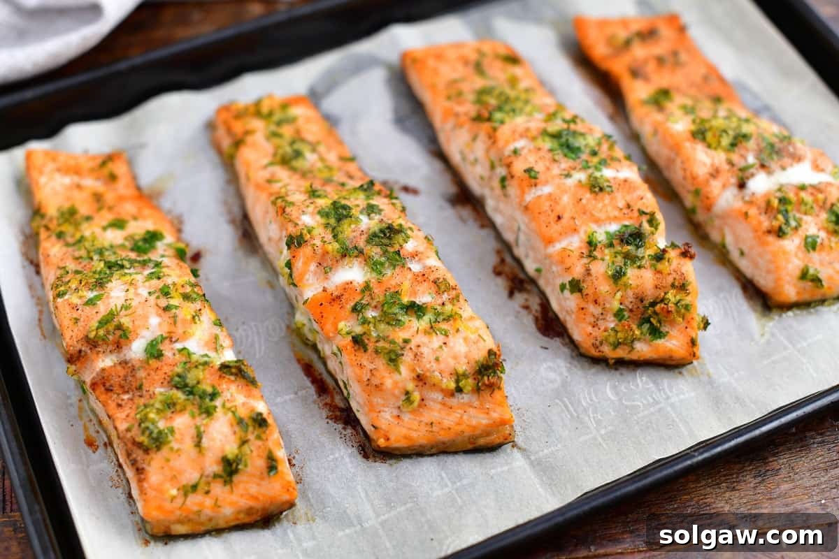 Oven baked salmon fillets garnished with fresh parsley and dill, ready to be served.