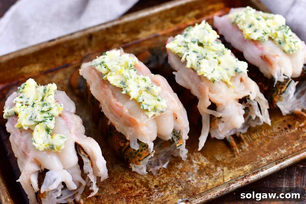 4 raw lobster tails topped with compound butter, ready for baking