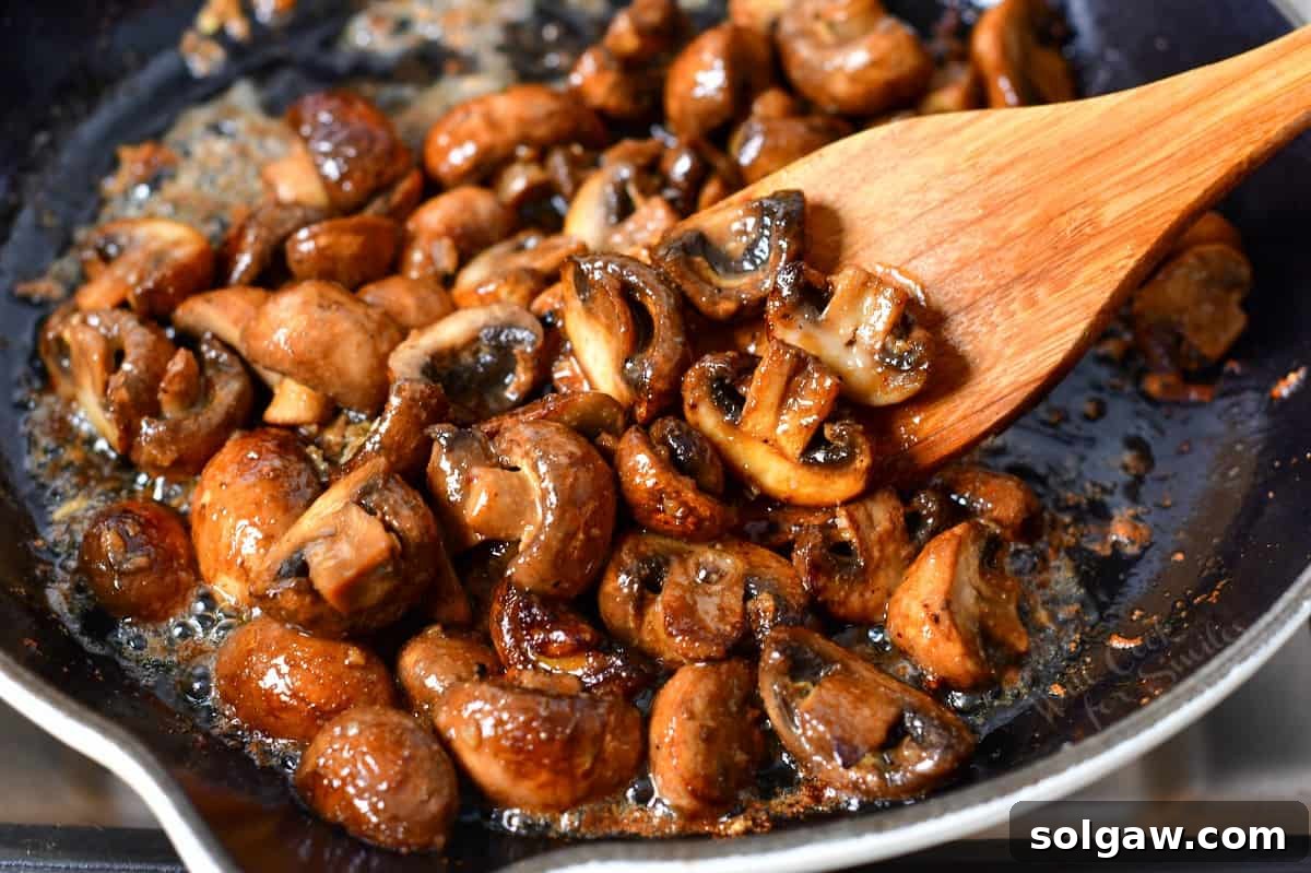 Stirring buttery, golden-brown sautéed mushrooms with a wooden spoon