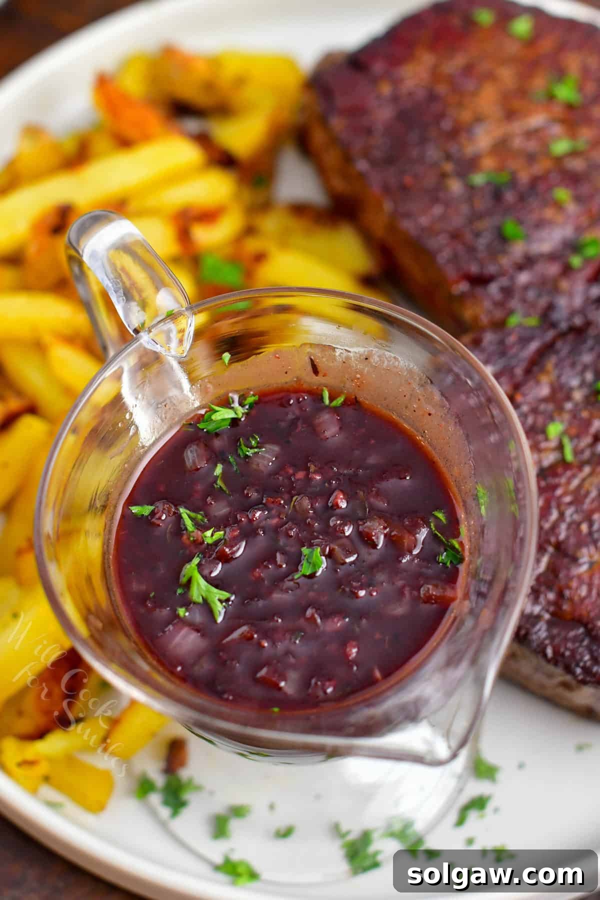 Close-up of a perfectly cooked steak drizzled with glossy red wine sauce, ready to be served.