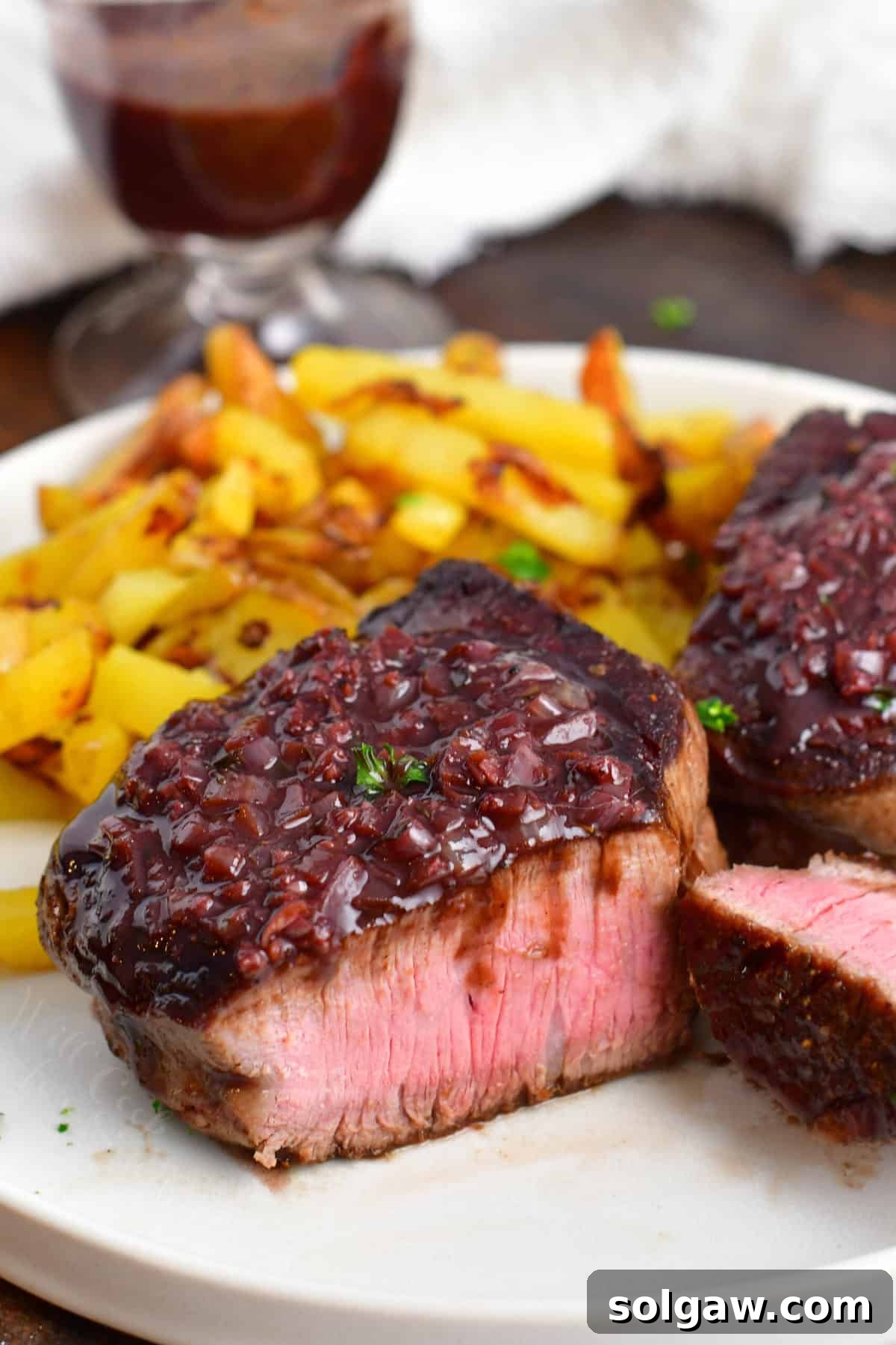 A beautifully plated steak dinner featuring a perfectly cooked steak with rich red wine sauce, mashed potatoes, and green beans.
