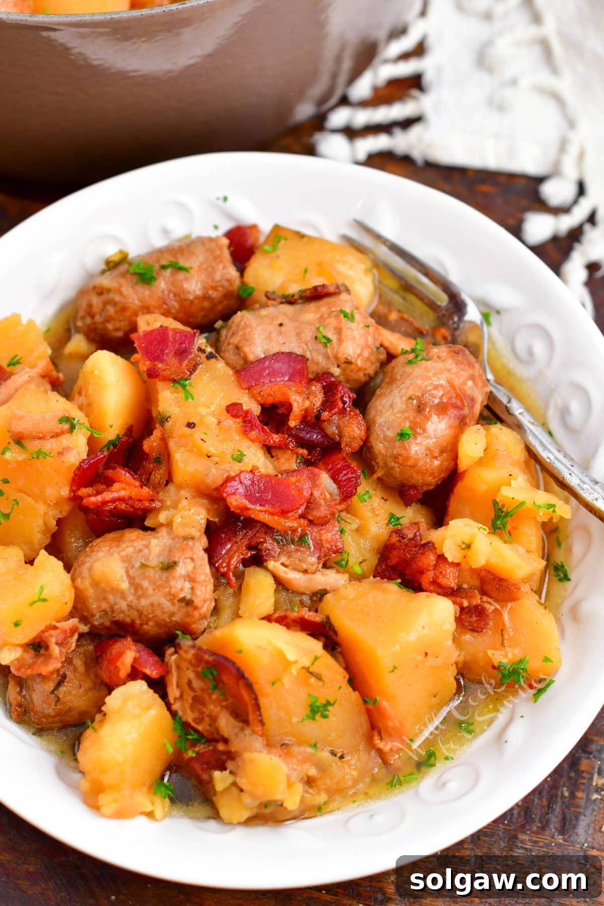 Dublin Coddle: Classic Irish Sausage and Potato Stew 2 A white plate contains a generous serving of Dublin Coddle, garnished with fresh herbs.
