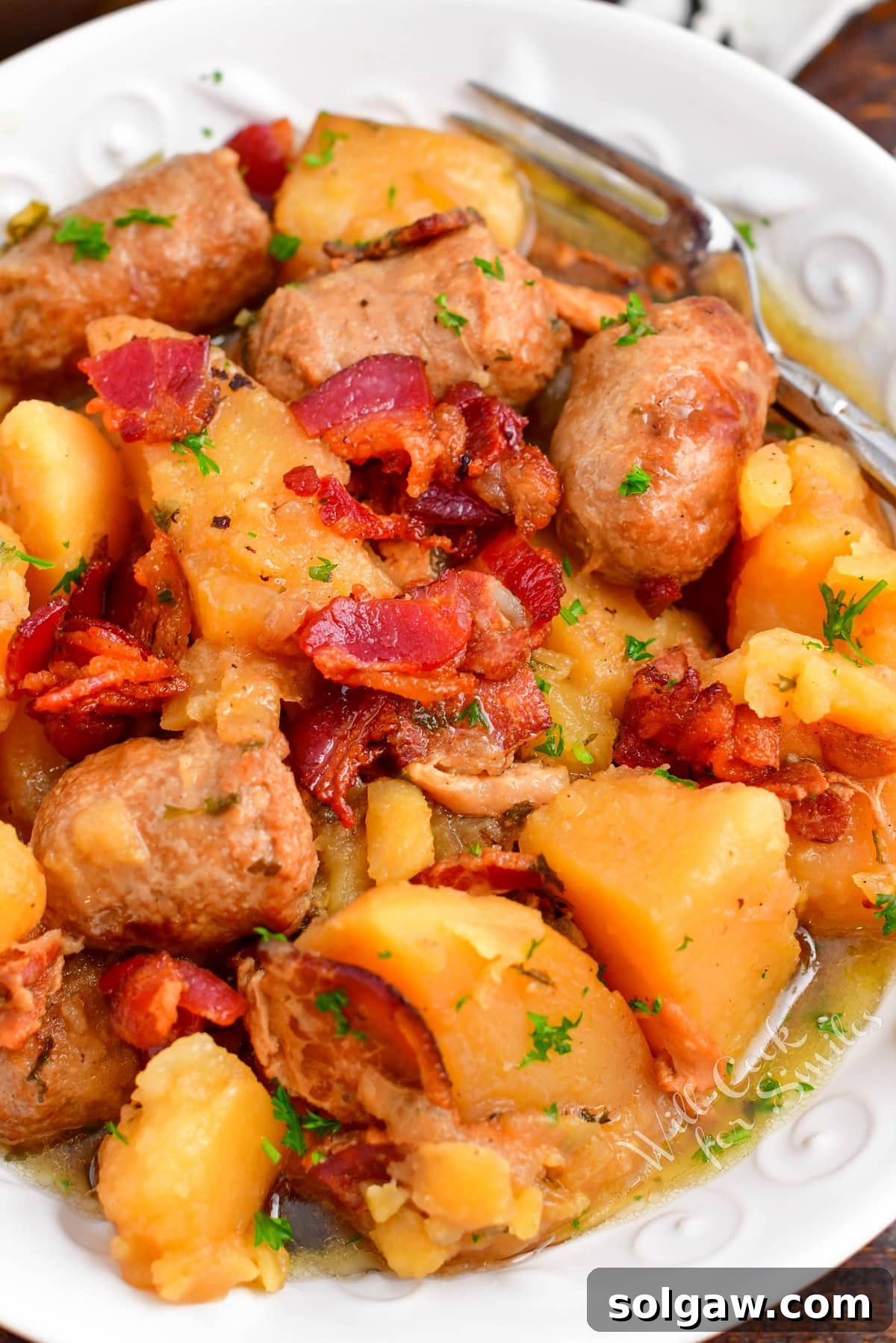 Dublin Coddle: Classic Irish Sausage and Potato Stew 11 A white bowl filled with coddle is garnished with crispy bacon pieces.