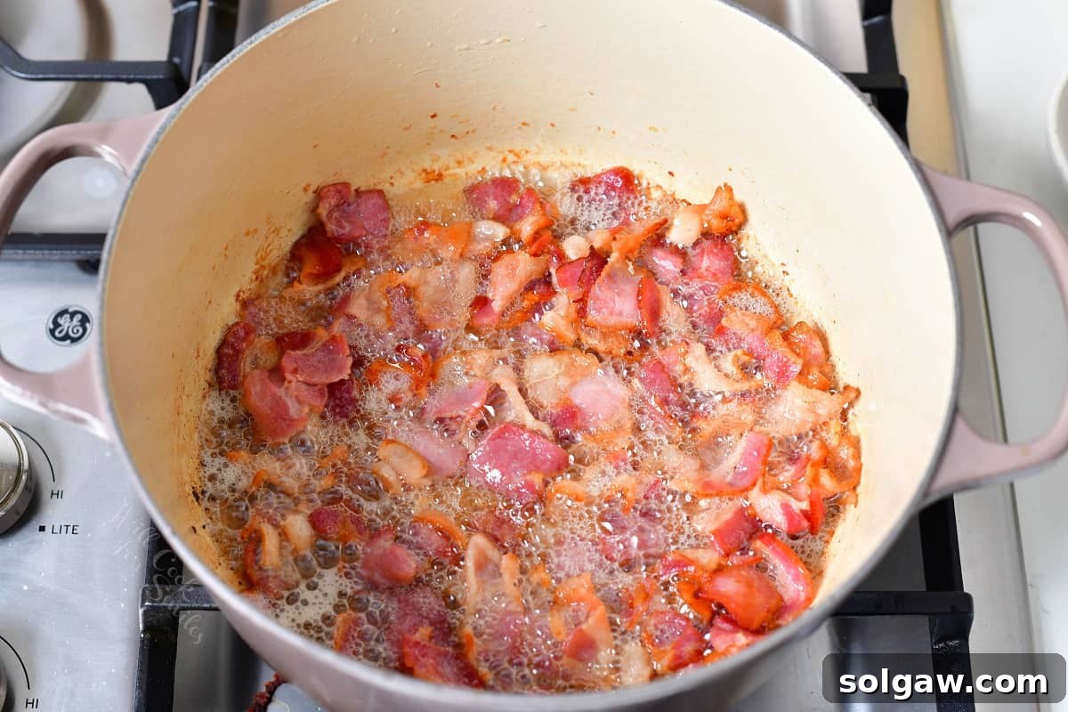 Dublin Coddle: Classic Irish Sausage and Potato Stew 4 Crispy bacon is being cooked at the bottom of a heavy-bottomed Dutch oven, rendering its fat.