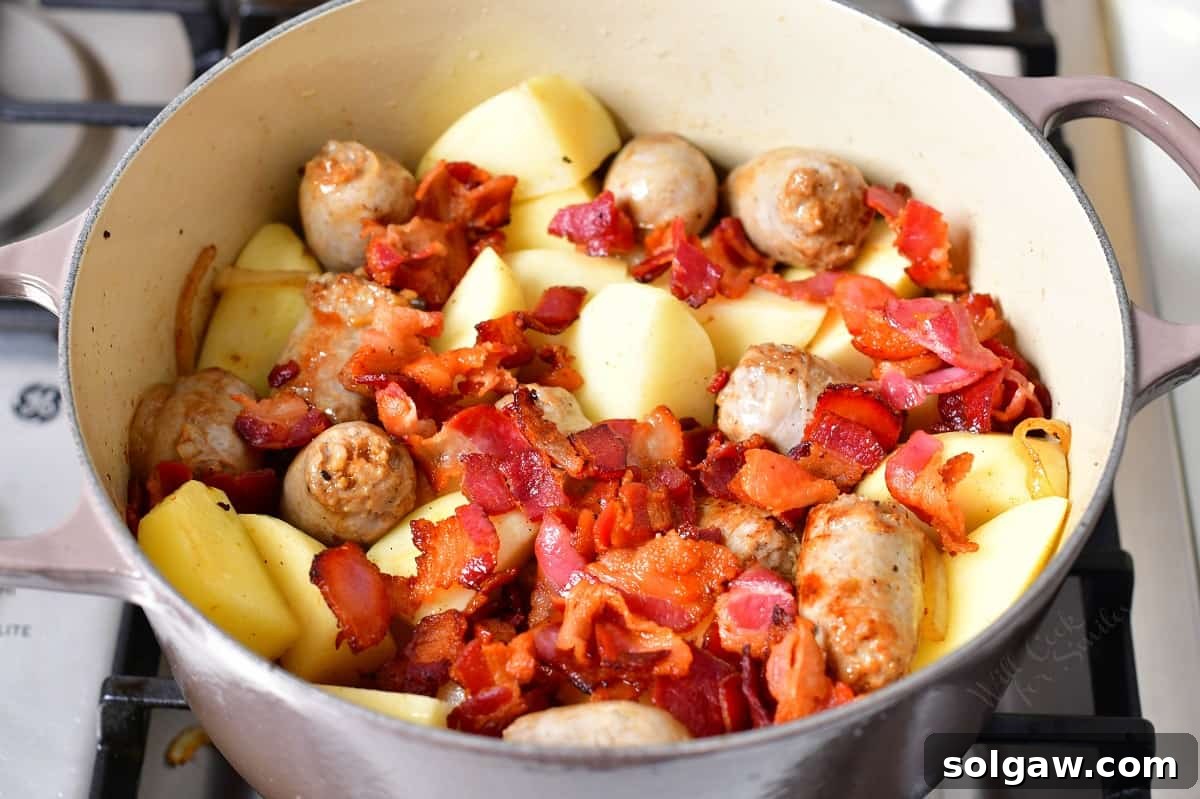 Dublin Coddle: Classic Irish Sausage and Potato Stew 6 Crispy bacon pieces and quartered russet potatoes have been added to the pot, layered over the seared sausages and onions.