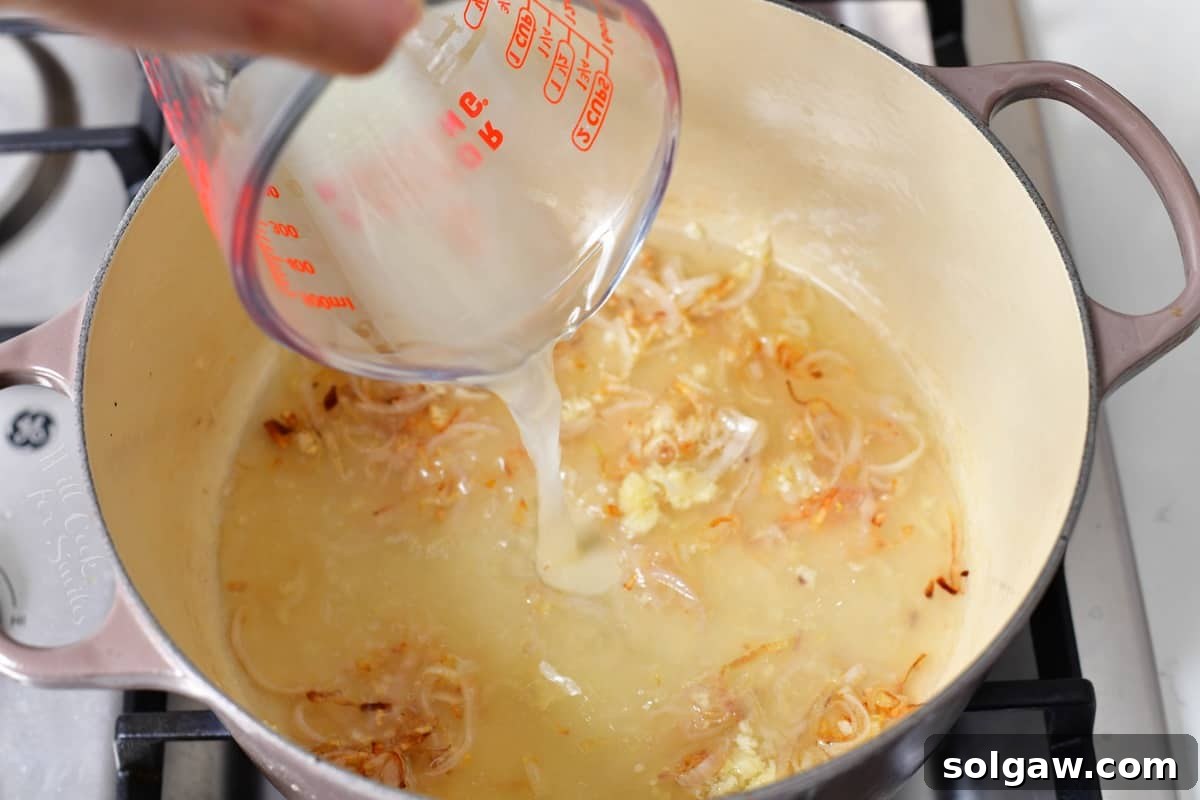The starchy pasta water being poured into a pot with sautéed shallots and garlic, forming the base of the sauce.