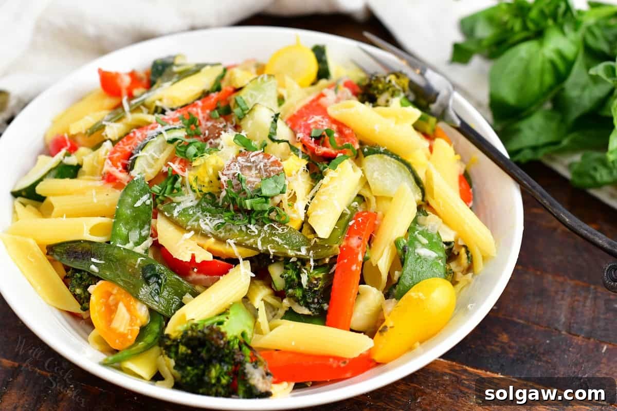 A freshly plated serving of pasta primavera, generously topped with grated Parmesan cheese and fresh herbs.