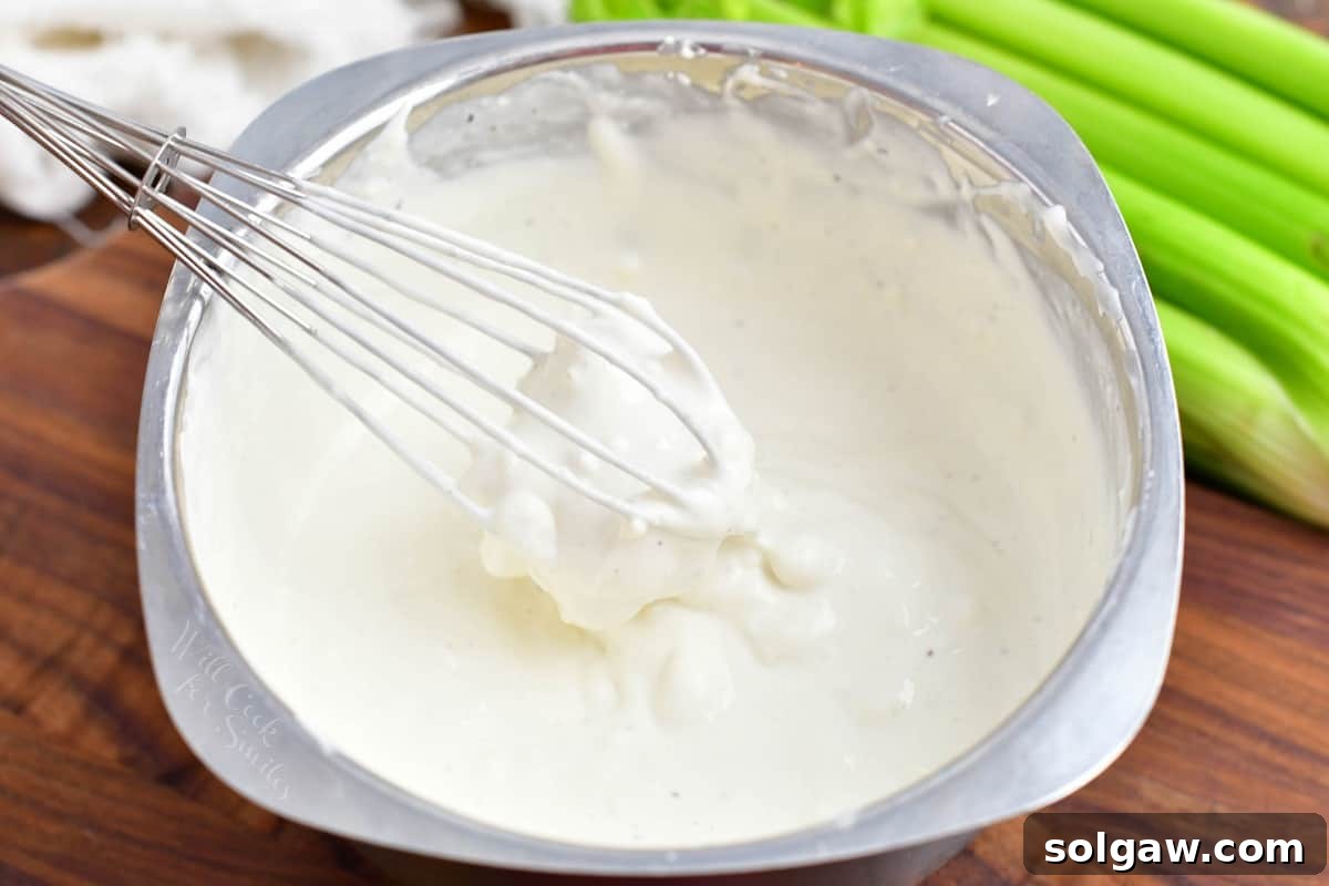 A whisk has combined all of the ingredients for blue cheese dressing.