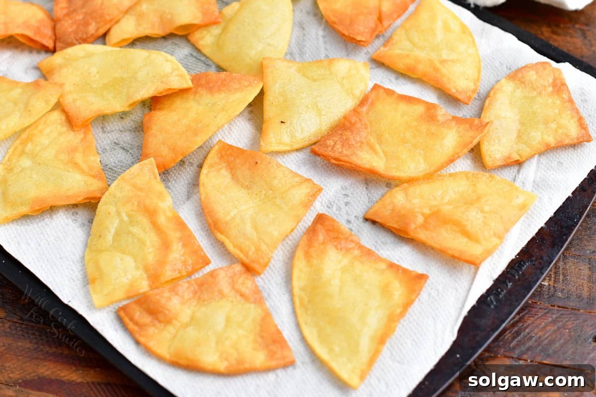 Tortilla chips being baked on a baking sheet, arranged in a single layer.