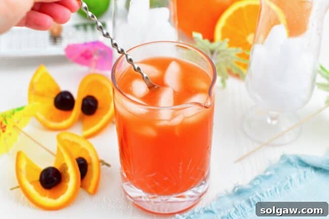 Tropical Rum Bliss 4 A stirring spoon is gracefully swirling the vibrant rum punch in a glass, mixing the flavors perfectly.